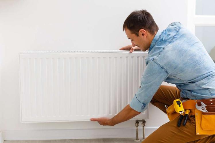Plumber installing or adjusting a home radiator heating unit