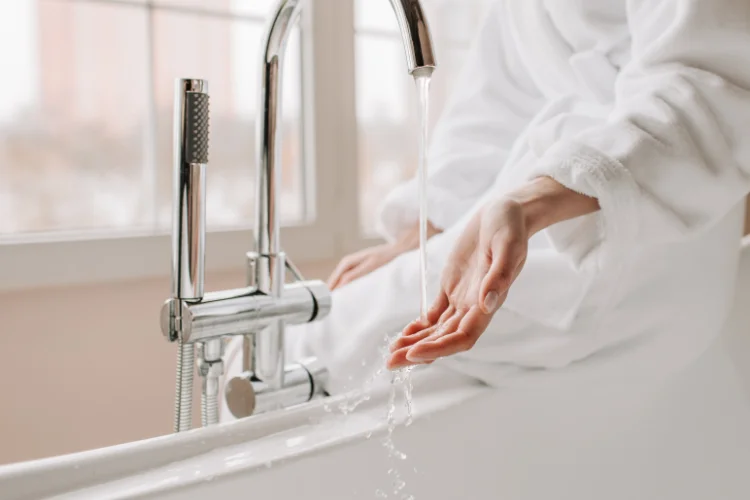 Person checking running water from a bathtub tap