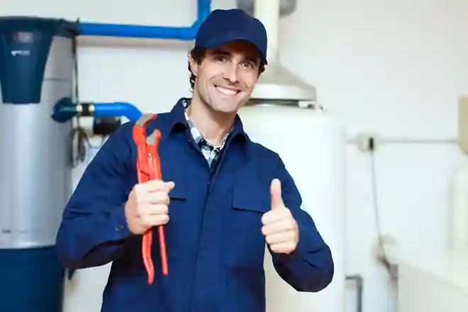 Smiling plumber giving thumbs up while holding plumbing tool
