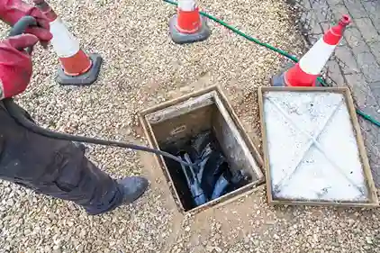 Worker unblocking an outdoor drain chamber